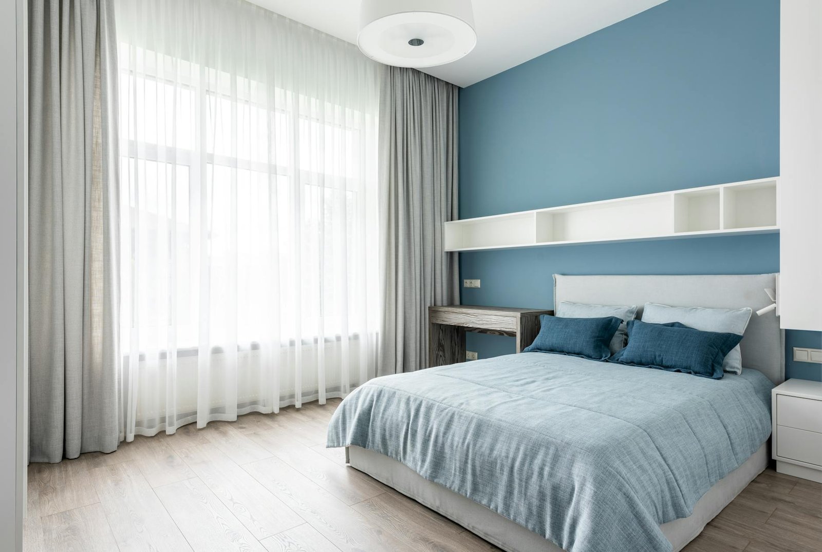 serene bedroom with cool blue tones blackout curtains partially drawn and a cozy bed with white linens ready for sleep